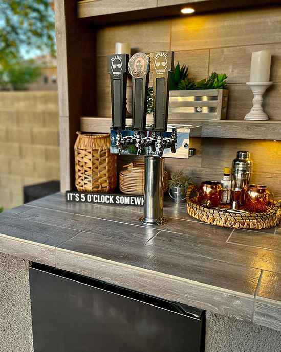 Outdoor bar setup with beer taps and decorative items on a wooden counter.